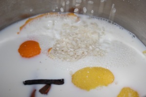En una cacerola, añadir leche, arroz, canela, vainilla, cáscaras de limón y naranja